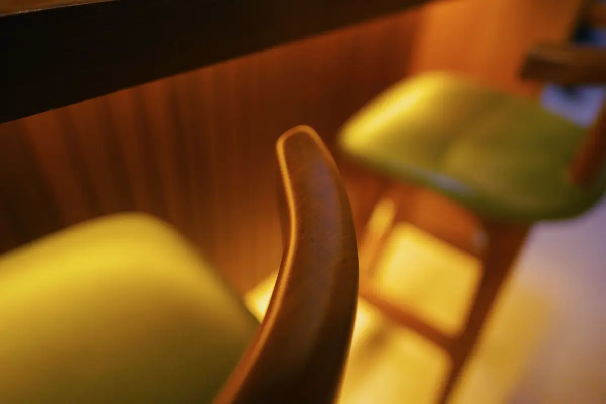 Close up detail shot of barstool green leather seat and curved wood backrest